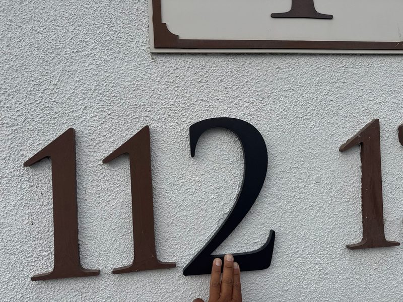 Dimensional building address numerals being mounted on a stucco wall