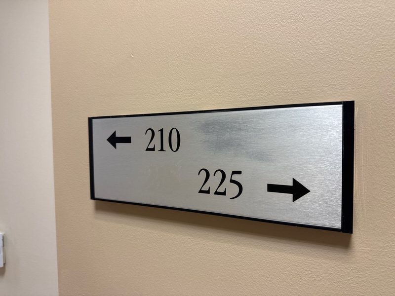 Interior directional wayfinding sign with arrows to rooms 210 and 225